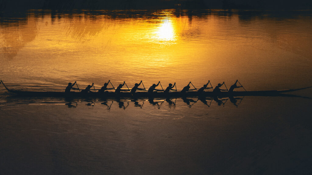 A team rowing a boat in the sunset